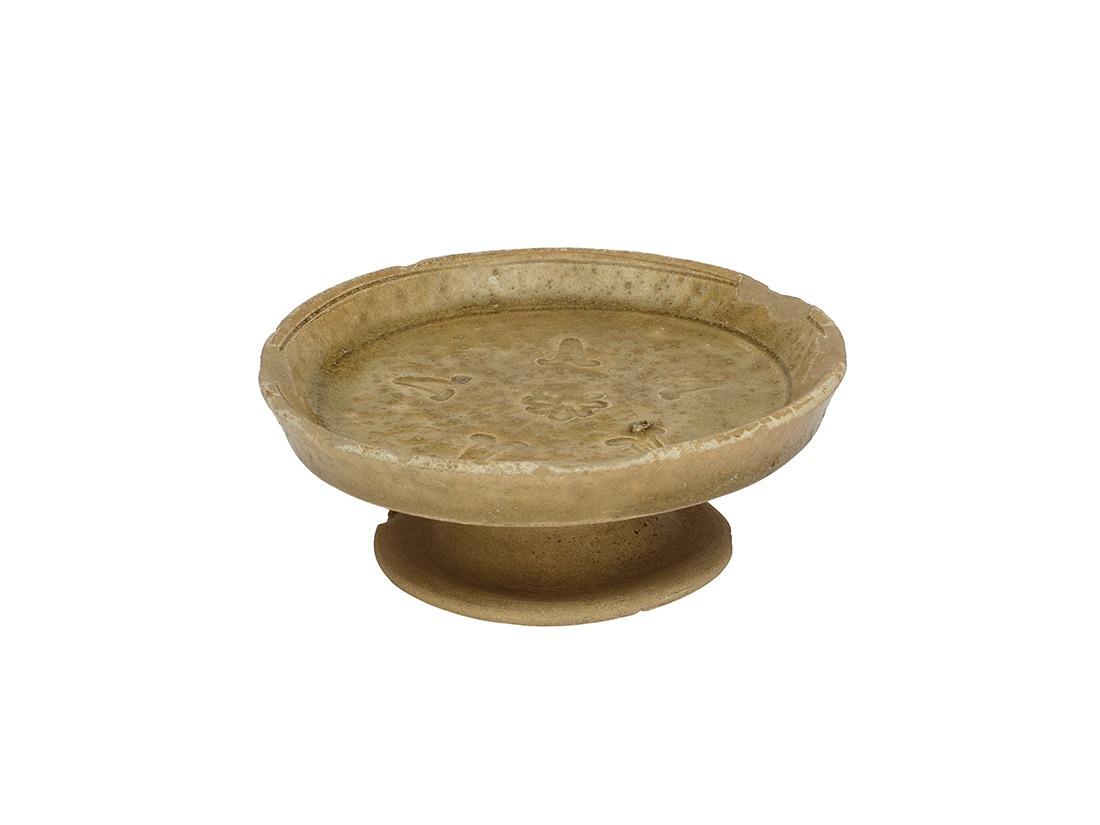 1995年香港大嶼山沙咀頭出土的唐朝青釉印花陶豆,盤面押印了菊花和牽牛花的圖案。(圖片來源:古物古蹟辦事處)