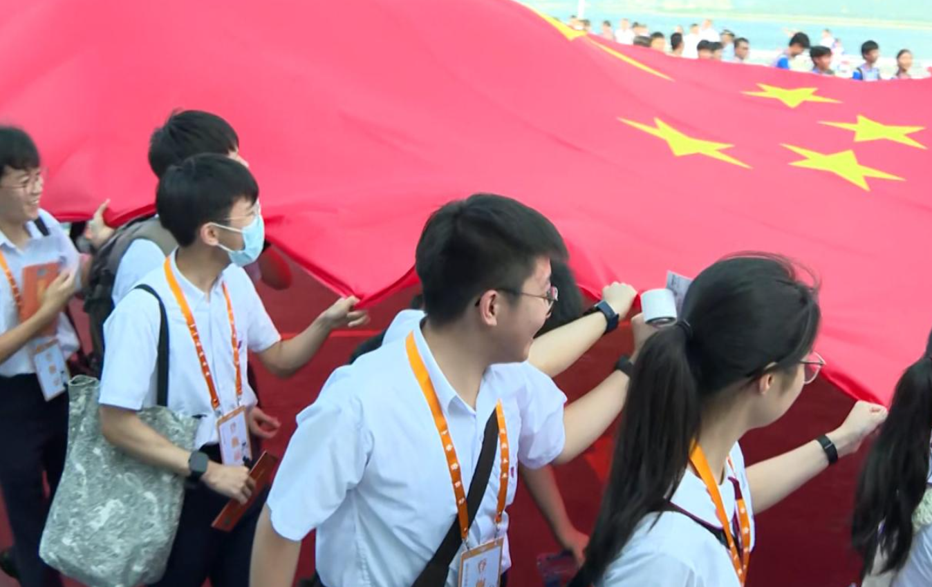 山東艦訪港|一眾師生在甲板上合力拉起一幅巨型的國旗。(港台圖片)