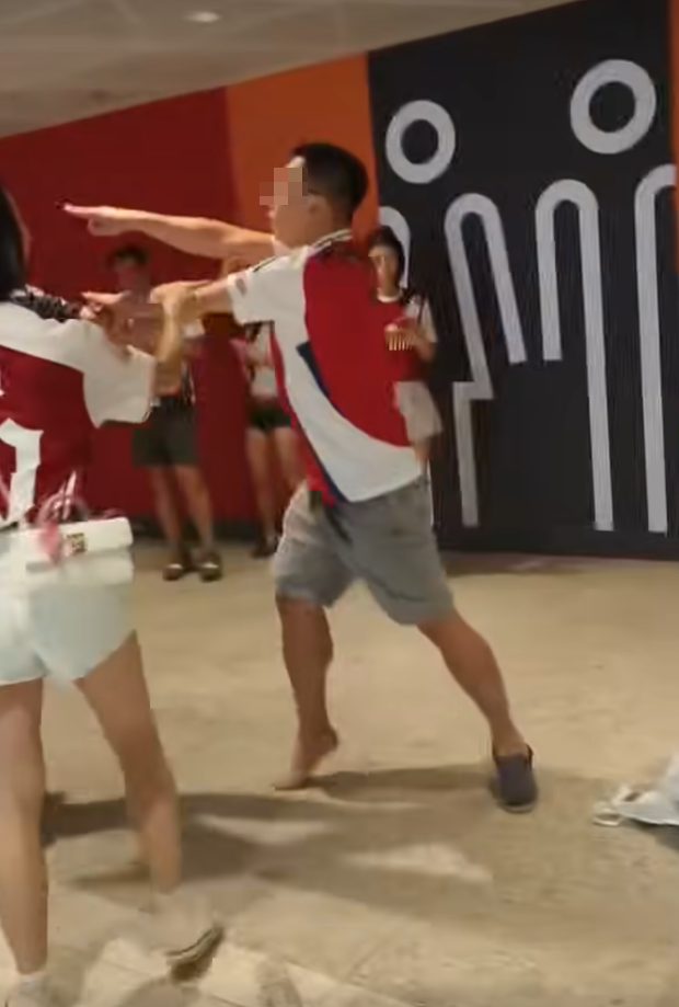 社交平台網上流傳一條影片,可見兩名分別穿上紅色及黑色阿仙奴球衣的男球迷在啟德主場館「內鬨」爭執講手,一名與黑衫男同行的女伴嘗試勸交,惟被誤打到口部。(影片截圖)