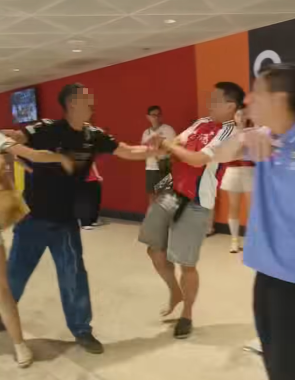 社交平台網上流傳一條影片,可見兩名分別穿上紅色及黑色阿仙奴球衣的男球迷在啟德主場館「內鬨」爭執講手,一名與黑衫男同行的女伴嘗試勸交,惟被誤打到口部。(影片截圖)