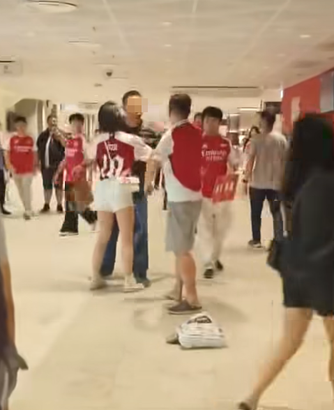 社交平台網上流傳一條影片,可見兩名分別穿上紅色及黑色阿仙奴球衣的男球迷在啟德主場館「內鬨」爭執講手,一名與黑衫男同行的女伴嘗試勸交,惟被誤打到口部。(影片截圖)