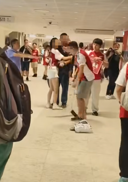 社交平台網上流傳一條影片,可見兩名分別穿上紅色及黑色阿仙奴球衣的男球迷在啟德主場館「內鬨」爭執講手,一名與黑衫男同行的女伴嘗試勸交,惟被誤打到口部。(影片截圖)