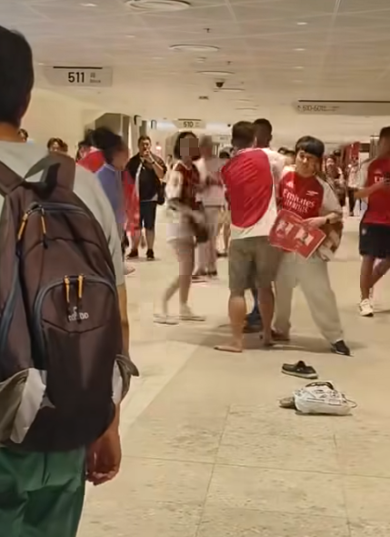 社交平台網上流傳一條影片,可見兩名分別穿上紅色及黑色阿仙奴球衣的男球迷在啟德主場館「內鬨」爭執講手,一名與黑衫男同行的女伴嘗試勸交,惟被誤打到口部。(影片截圖)