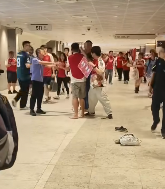 社交平台網上流傳一條影片,可見兩名分別穿上紅色及黑色阿仙奴球衣的男球迷在啟德主場館「內鬨」爭執講手,一名與黑衫男同行的女伴嘗試勸交,惟被誤打到口部。(影片截圖)