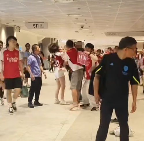 社交平台網上流傳一條影片,可見兩名分別穿上紅色及黑色阿仙奴球衣的男球迷在啟德主場館「內鬨」爭執講手,一名與黑衫男同行的女伴嘗試勸交,惟被誤打到口部。(影片截圖)