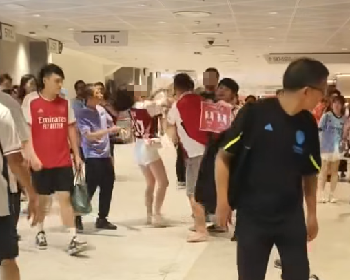 社交平台網上流傳一條影片,可見兩名分別穿上紅色及黑色阿仙奴球衣的男球迷在啟德主場館「內鬨」爭執講手,一名與黑衫男同行的女伴嘗試勸交,惟被誤打到口部。(影片截圖)