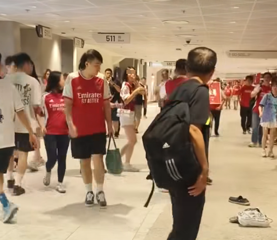 社交平台網上流傳一條影片,可見兩名分別穿上紅色及黑色阿仙奴球衣的男球迷在啟德主場館「內鬨」爭執講手,一名與黑衫男同行的女伴嘗試勸交,惟被誤打到口部。(影片截圖)