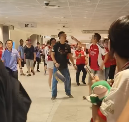 社交平台網上流傳一條影片,可見兩名分別穿上紅色及黑色阿仙奴球衣的男球迷在啟德主場館「內鬨」爭執講手,一名與黑衫男同行的女伴嘗試勸交,惟被誤打到口部。(影片截圖)