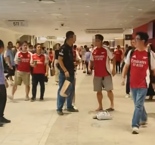 社交平台網上流傳一條影片,可見兩名分別穿上紅色及黑色阿仙奴球衣的男球迷在啟德主場館「內鬨」爭執講手,一名與黑衫男同行的女伴嘗試勸交,惟被誤打到口部。(影片截圖)