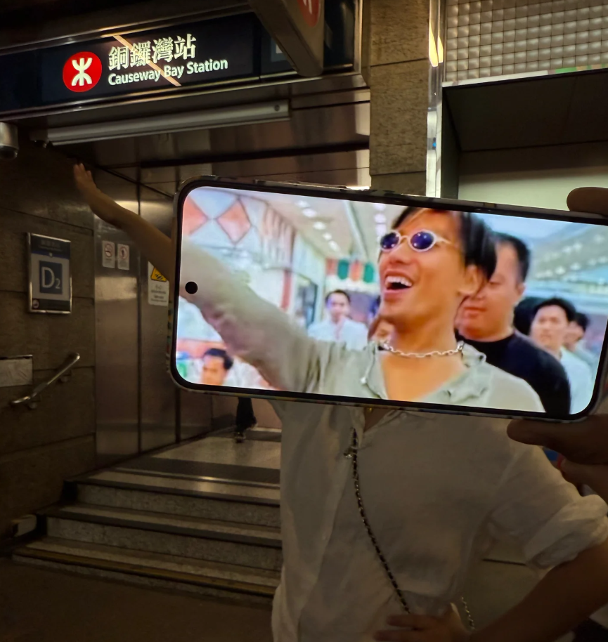 照片可見有旅客左手以手機拍攝期間,右手舉起另一手機展示1996年港產電影《古惑仔3之隻手遮天》電影、由張耀揚演出的反派角色「烏鴉」於進入酒樓出席關帝君誕辰宴會的經典打招呼手勢劇照(小紅書)