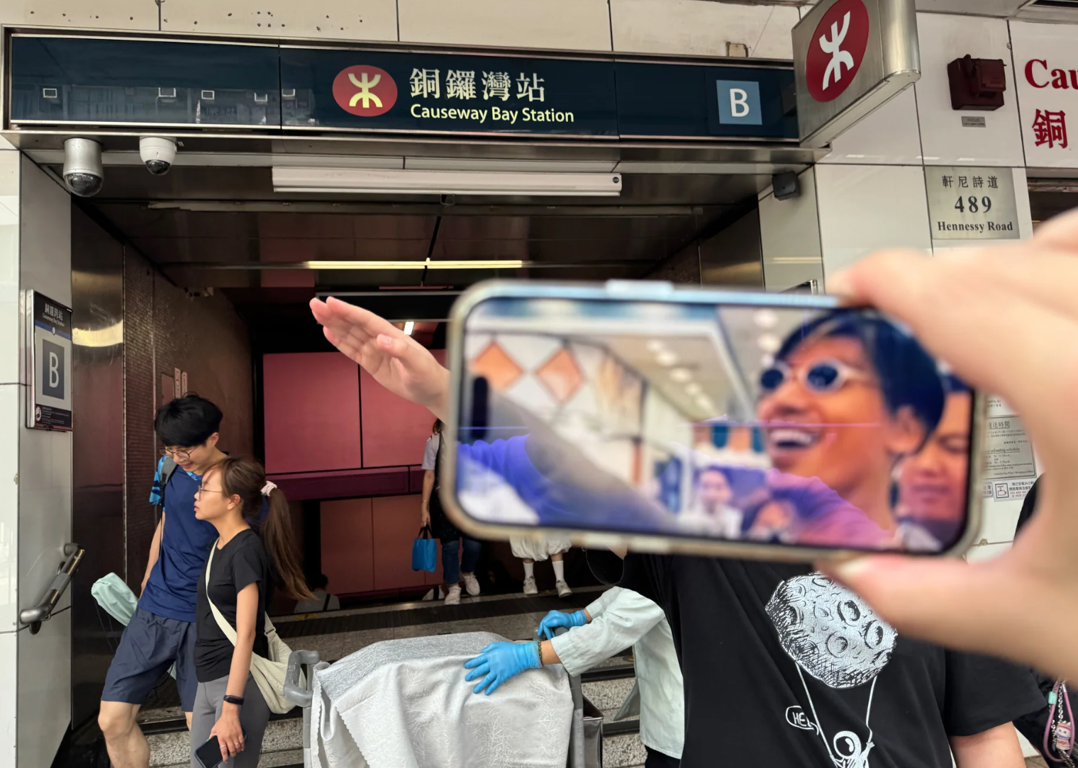 照片可見有旅客左手以手機拍攝期間,右手舉起另一手機展示1996年港產電影《古惑仔3之隻手遮天》電影、由張耀揚演出的反派角色「烏鴉」於進入酒樓出席關帝君誕辰宴會的經典打招呼手勢劇照(小紅書)