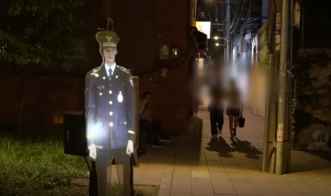 南韓首爾警方為減低犯罪率,在一個治安黑點公園設置投影警察「站崗」,警方表示設置裝置後,公園周邊犯罪率較同年下降22%(影片截圖)