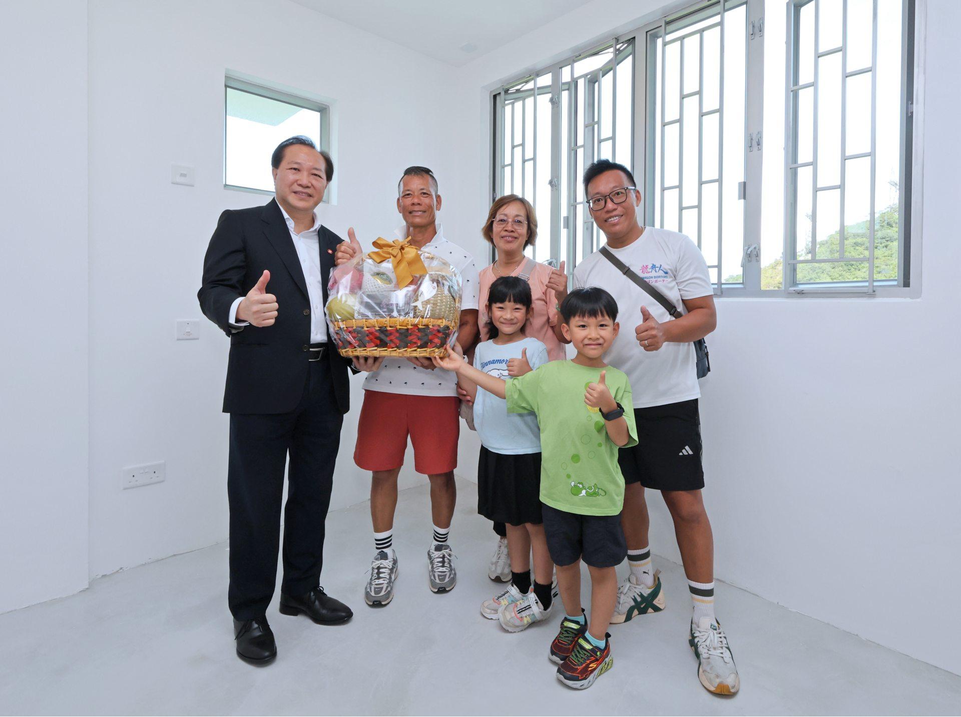 房協總監(物業管理)潘源舫(左一)參觀首位住戶鄭太新居入伙,恭賀其一家展開新生活。