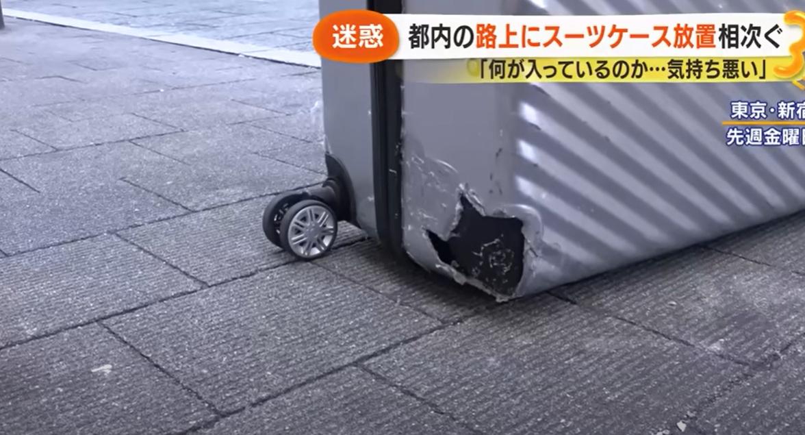 日本媒體報道,有人在東京新宿鬧市丟棄毀爛的舊行李箱。(互聯網)