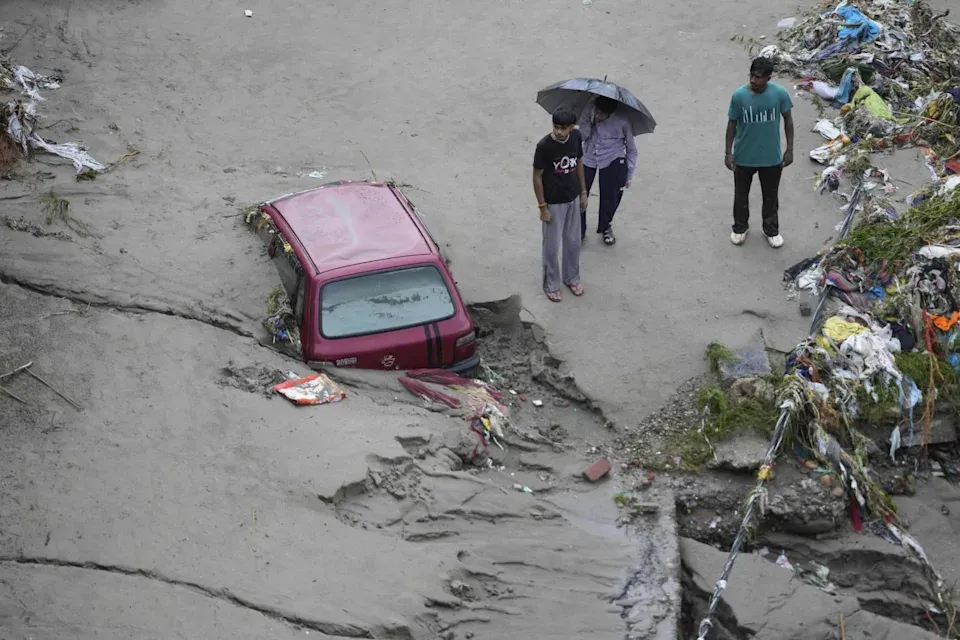 塔維河水氾濫後,人們站在一輛被困的汽車旁。(圖/美聯社)