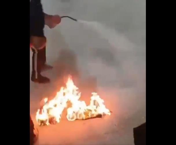 男子在地上焚燒,保安等人向他噴化學滅火劑。(互聯網)