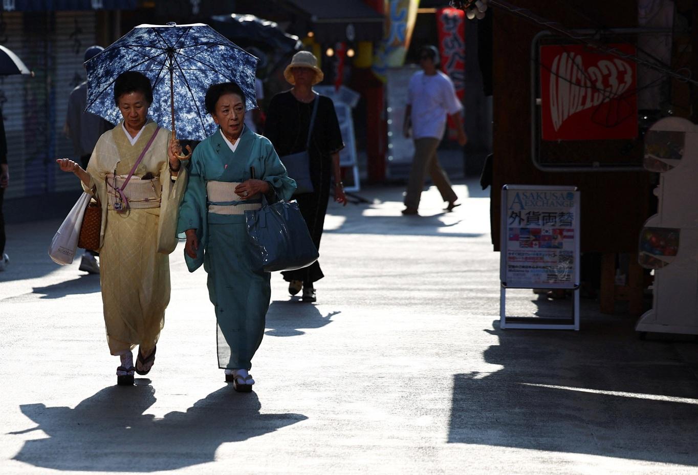 圖為東京等多地本月初天氣酷熱,當局發布中暑警報,兩名穿和服的婦女外出時撐傘。(資料圖片)