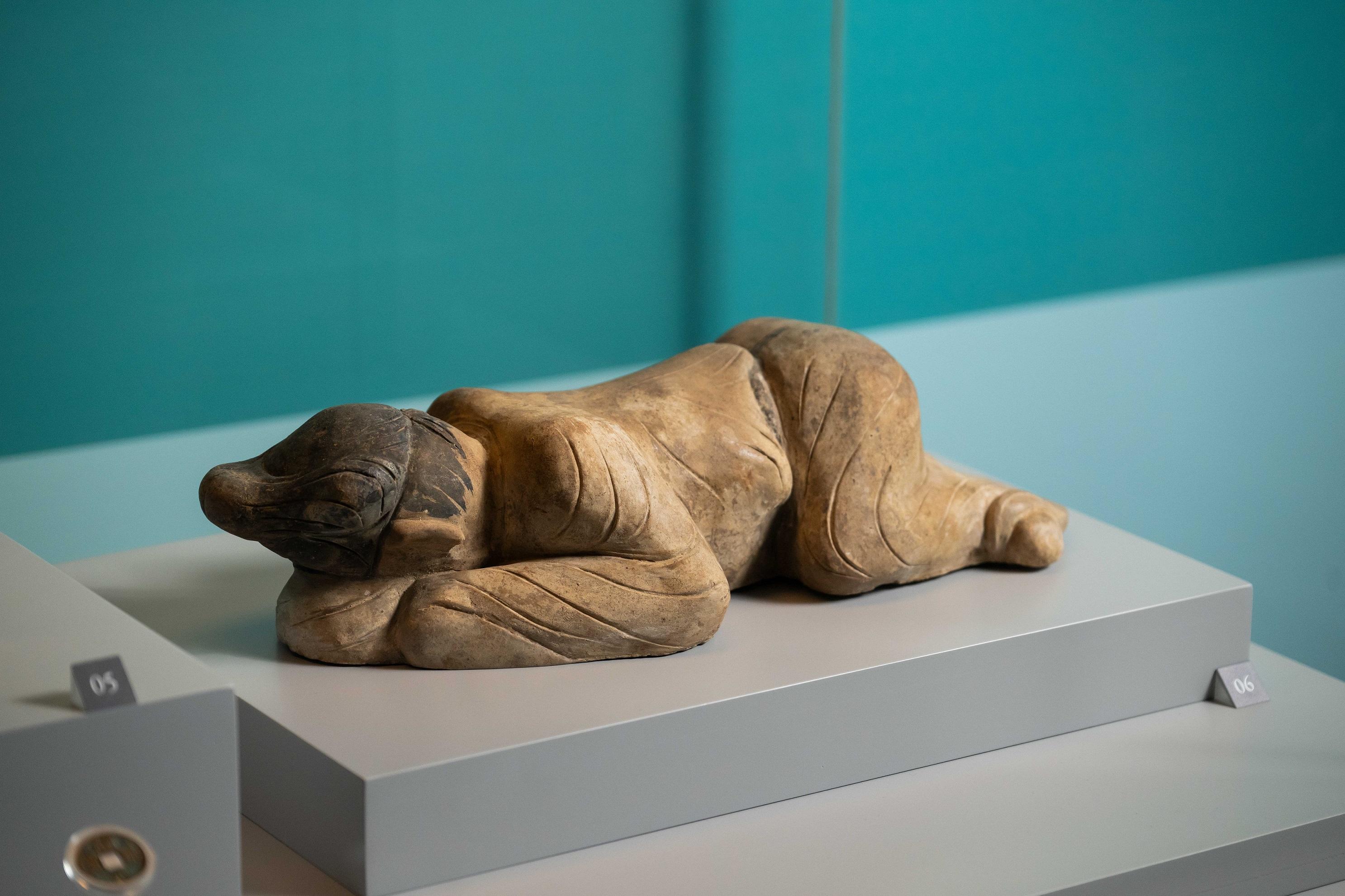 在甘肅慶城穆泰墓出土的「彩繪跪爬俑」頭部低垂貼近地面,彷彿專注聆聽地下動靜。(慶城縣博物館藏)