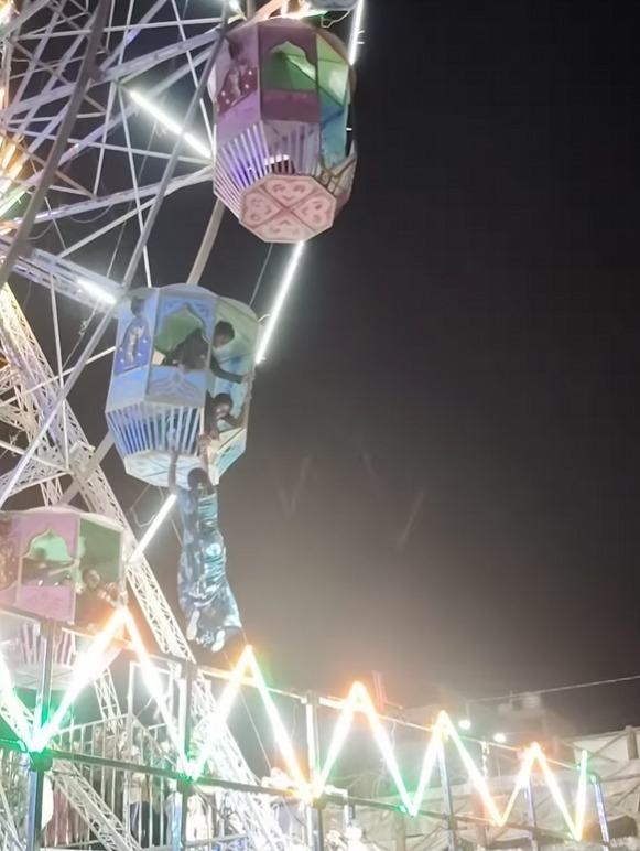 女子以雙手拉住摩天輪車廂底部。(影片截圖)