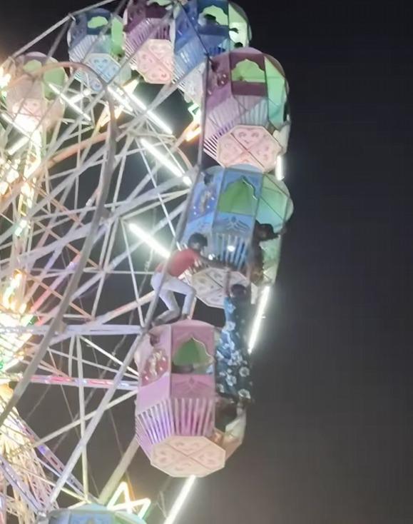 當地工作人員「零裝備」下爬到摩天輪車廂上協助女子。(影片截圖)