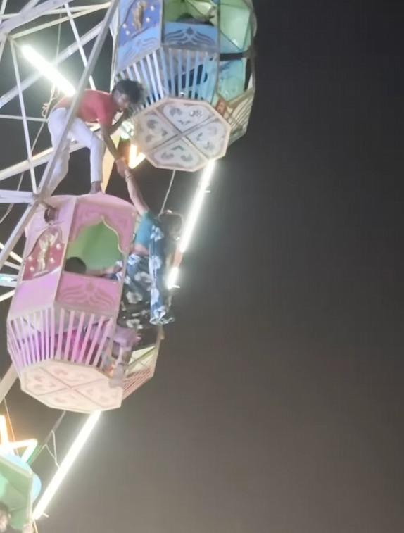 女子獲協助下爬回摩天輪車廂內。(影片截圖)