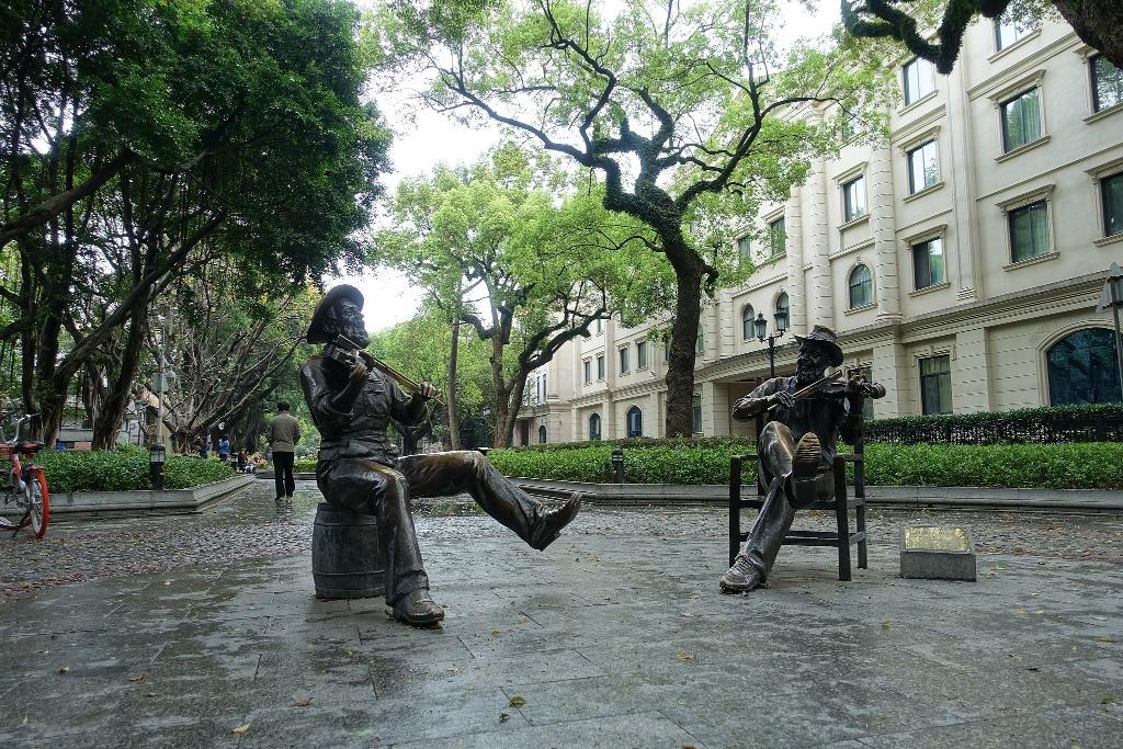 活化後的沙面,保留歐式建築外,還有多株百年古樹,公園內還有不少一對對的雕塑,反映當時中西方的交流。圖為Happy Hour(歡樂時光),由中國人及外國人分別演奏中西樂器,展示當年沙面的情景。(圖片來源:視覺中國)