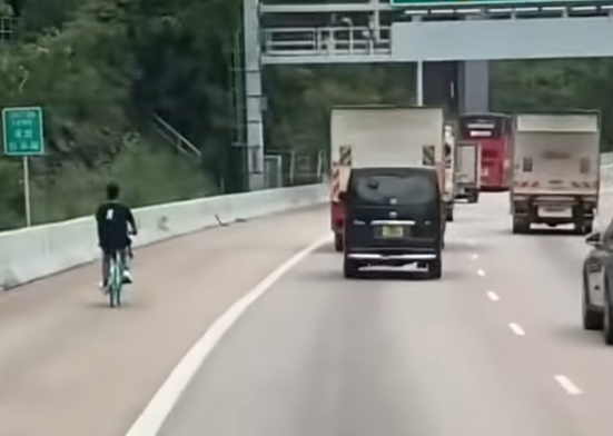 一名男子在屯門公路上沿着路肩踩共享單車。(影片截圖)