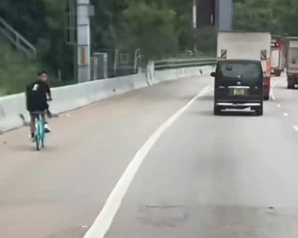一名男子在屯門公路上沿着路肩踩共享單車。(影片截圖)