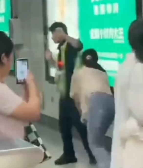 深圳地鐵女乘客以拳頭及手袋激烈追打一名的男安檢員,男方僅用手阻擋及後退,其後另外一名女安檢員上前制止,亦被女乘客用手袋重擊頭部。男安檢員隨即反手擒拿將女乘客制服,隨後女乘客躺臥在地不動。(影片截圖)