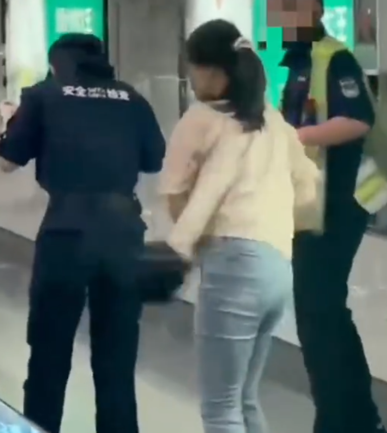 深圳地鐵女乘客以拳頭及手袋激烈追打一名的男安檢員,男方僅用手阻擋及後退,其後另外一名女安檢員上前制止,亦被女乘客用手袋重擊頭部。男安檢員隨即反手擒拿將女乘客制服,隨後女乘客躺臥在地不動。(影片截圖)