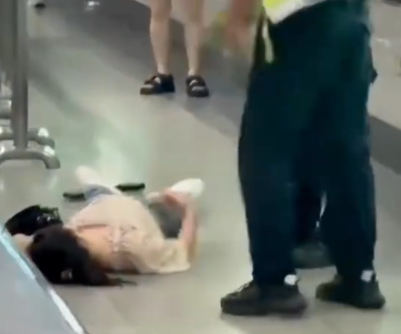 深圳地鐵女乘客以拳頭及手袋激烈追打一名的男安檢員,男方僅用手阻擋及後退,其後另外一名女安檢員上前制止,亦被女乘客用手袋重擊頭部。男安檢員隨即反手擒拿將女乘客制服,隨後女乘客躺臥在地不動。(影片截圖)
