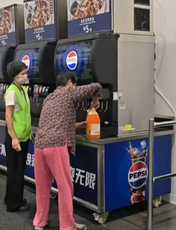 在武漢的一間山姆超市,一位中年大媽在飲食區手持大膠樽,在店內免費添飲續杯飲料吧裝滿了一整桶飲料,不顧員工在旁勸阻(影片截圖)
