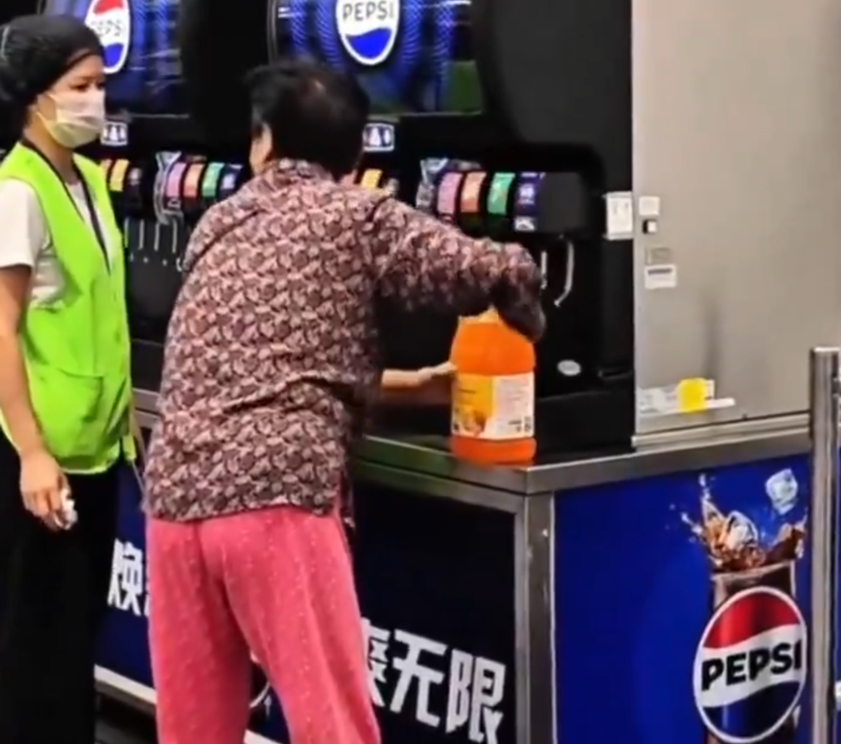 在武漢的一間山姆超市,一位中年大媽在飲食區手持大膠樽,在店內免費添飲續杯飲料吧裝滿了一整桶飲料,不顧員工在旁勸阻(影片截圖)