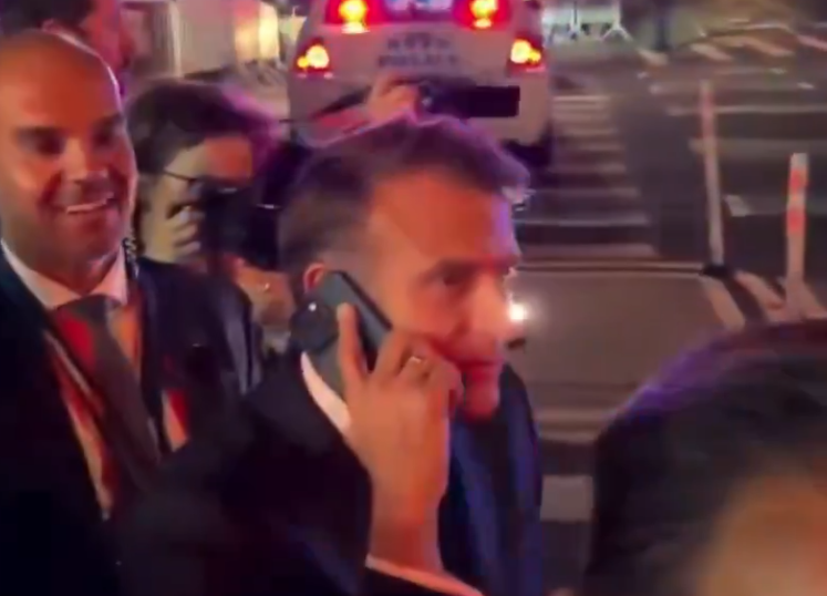 馬克龍想過馬路,但被警員攔下,須在路邊等候,他於是打給特朗普「投訴」。(互聯網)