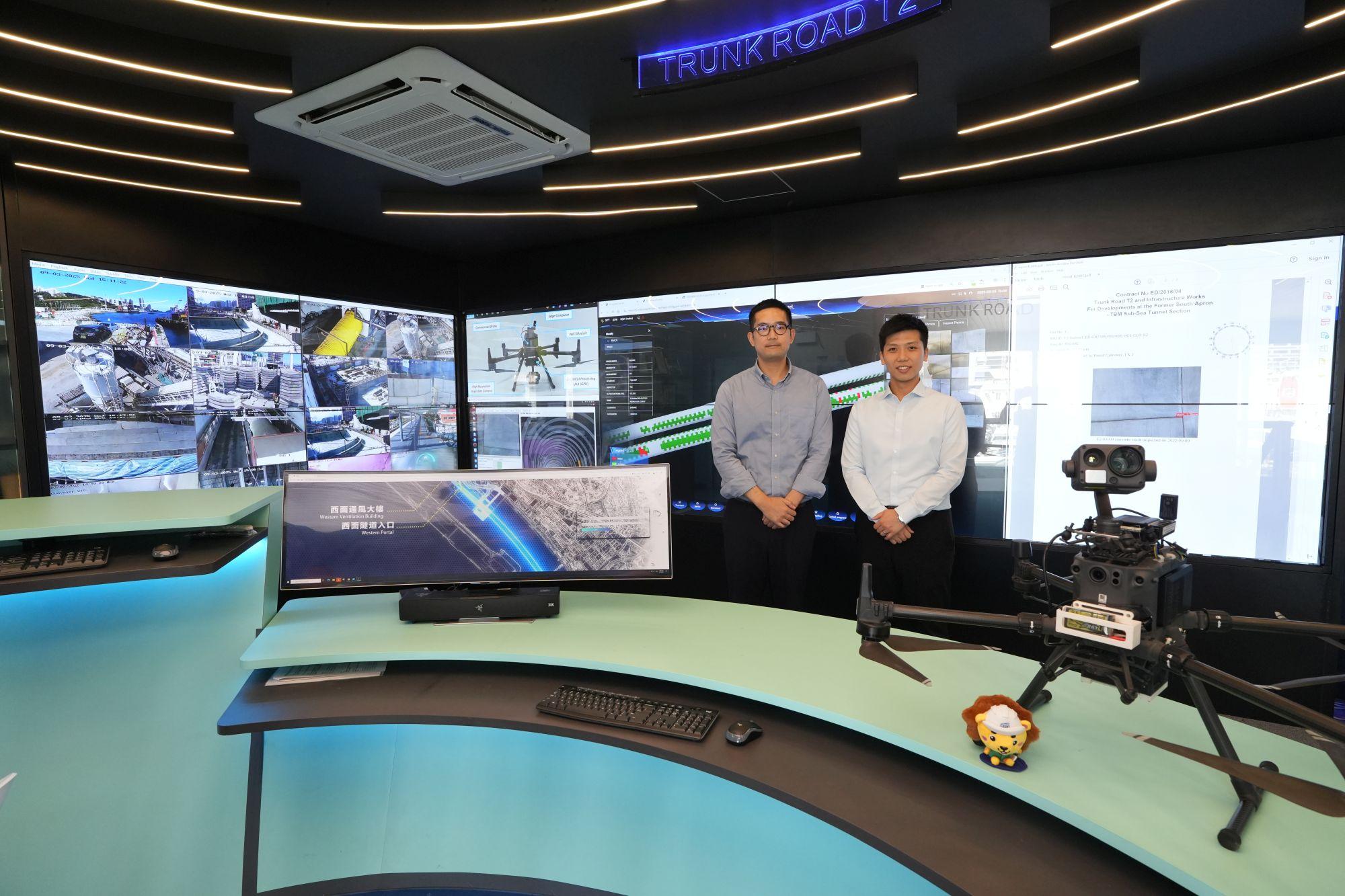 發展局助理秘書長(計劃管理)羅梓馨(右)和土木工程拓展署工程師馬浩斌(左)介紹土木工程拓展署在「T2主幹路及茶果嶺隧道」工程中應用的鑽孔機械人和「智能隧道質量檢測系統」。