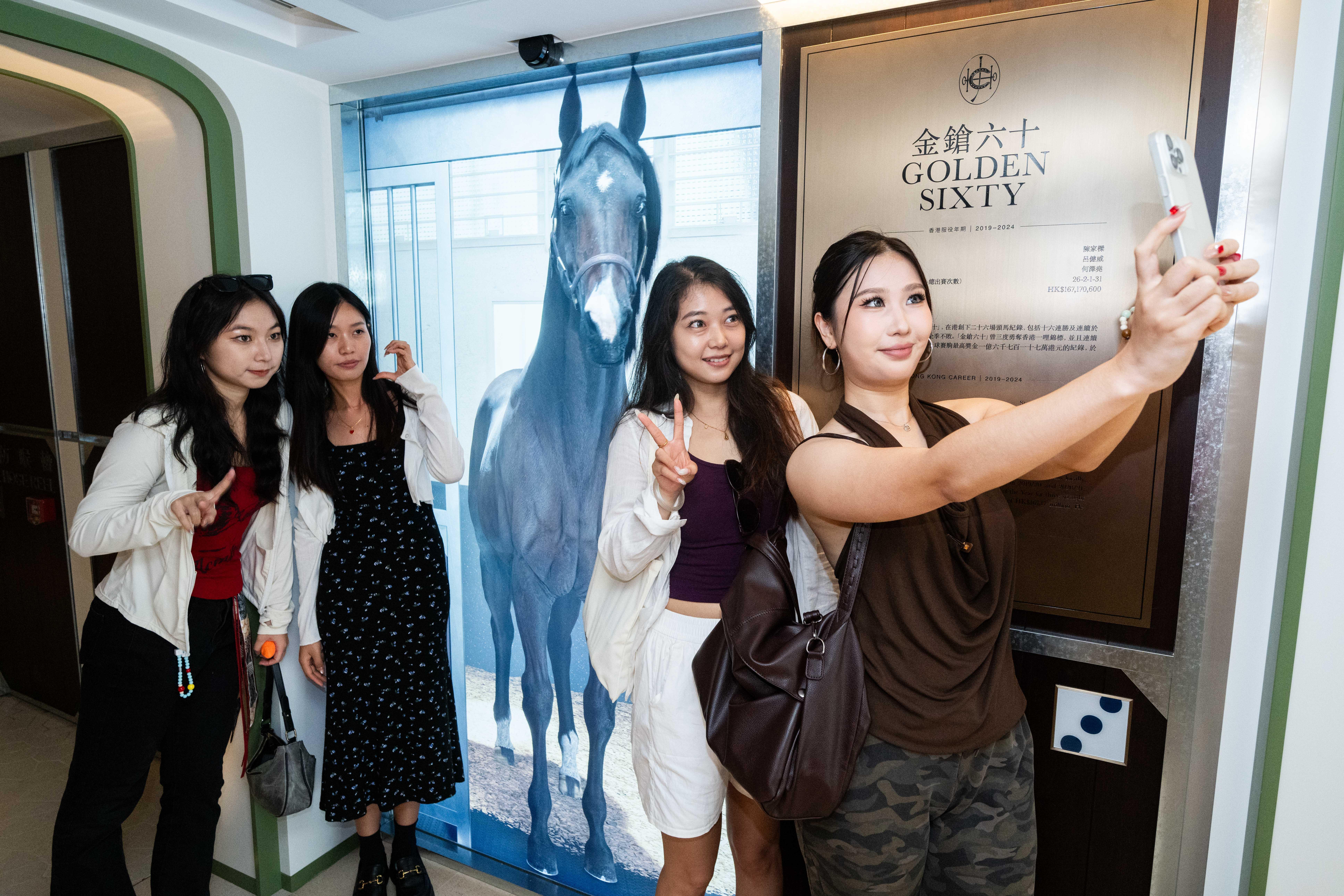重慶旅客畢小姐(右一)和朋友張小姐(右二)等友人一同參觀新啟用的「連薈」,率先體驗數碼互動設施,並與3D數碼技術還原的三屆香港馬王「金鎗六十」在虛擬馬房中互動