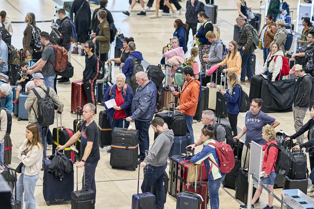 歐洲多個主要機場的自動報到系統遭網攻,造成航班混亂,圖為周一德國柏林機場大批旅客等候辦理登機手續。(美聯社)