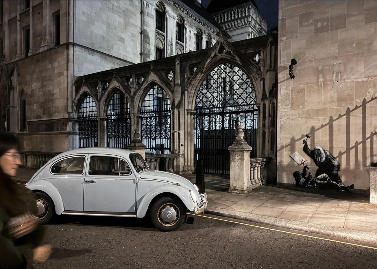 Banksy具諷刺意味的作品繪畫在倫敦皇家司法院外牆上。(路透社)