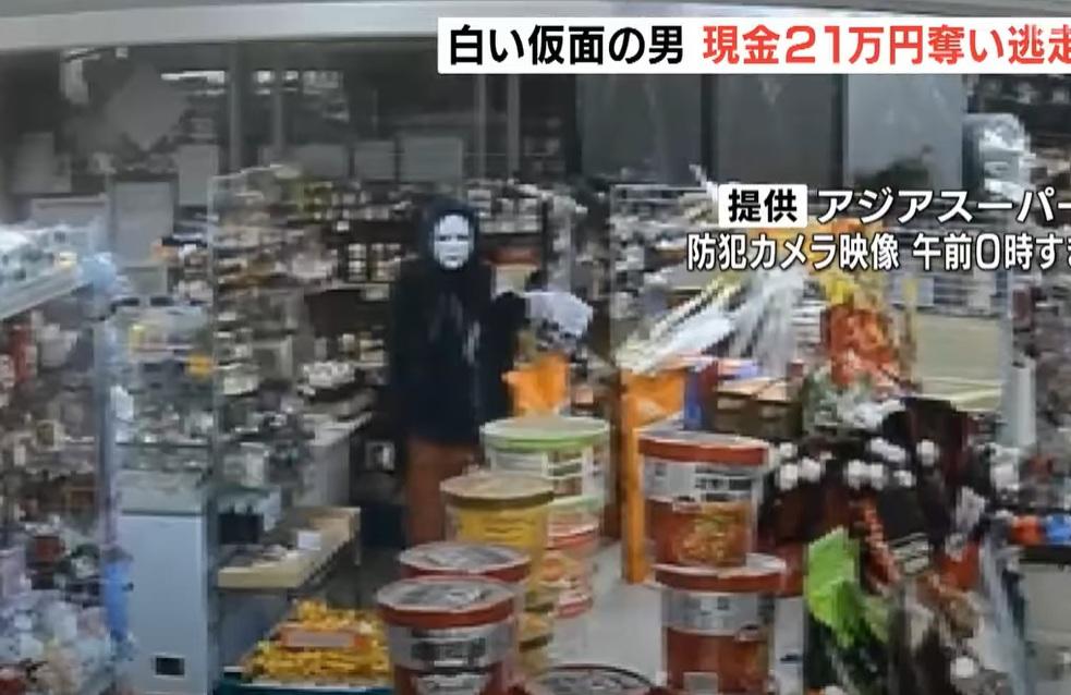劫匪戴著白色面具,身穿黑外套,深夜持刀進入超市。(互聯網)