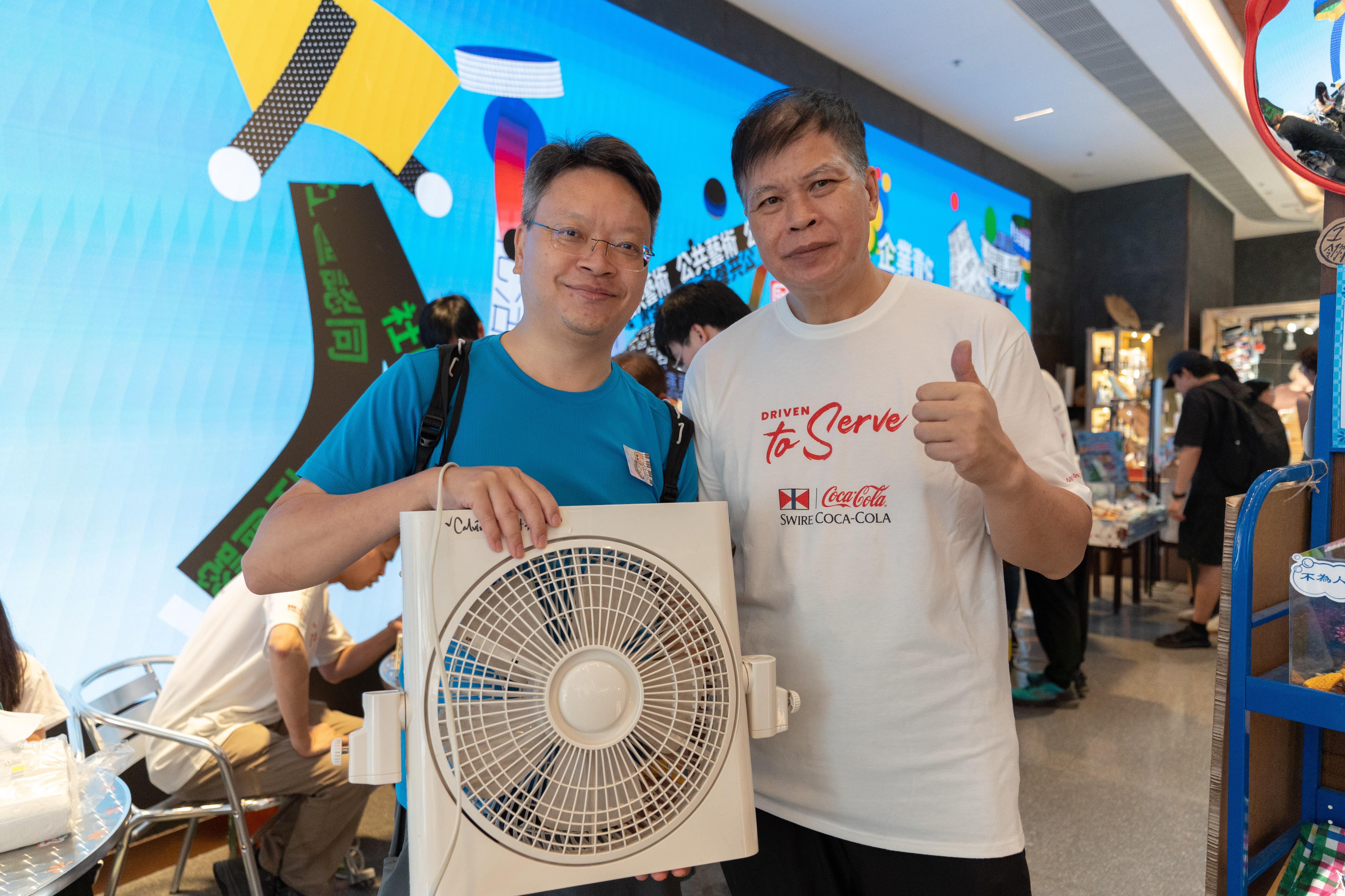 太古可口可樂技術員火哥(右)一雙巧手修理,恢復運作。物主Calvin(左)滿面笑容,大讚好掂,將風扇帶回家使用。