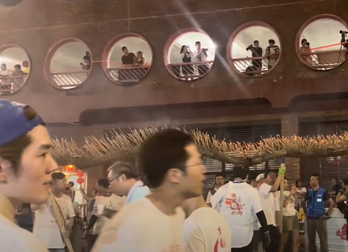 洪助昇(左)有份舞火龍,雖然鏡頭不太清楚,但因為只得他一人戴藍色帽去舞火龍,所以很易認到。