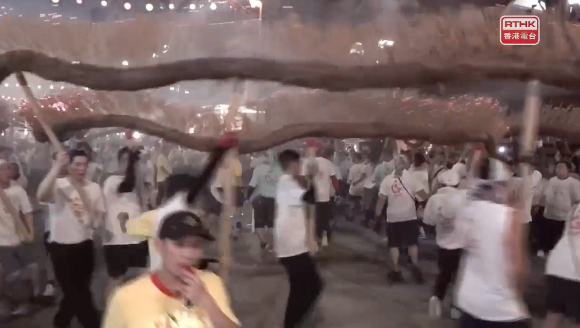 洪助昇(左)有份舞火龍,雖然鏡頭不太清楚,但因為只得他一人戴藍色帽去舞火龍,所以很易認到。