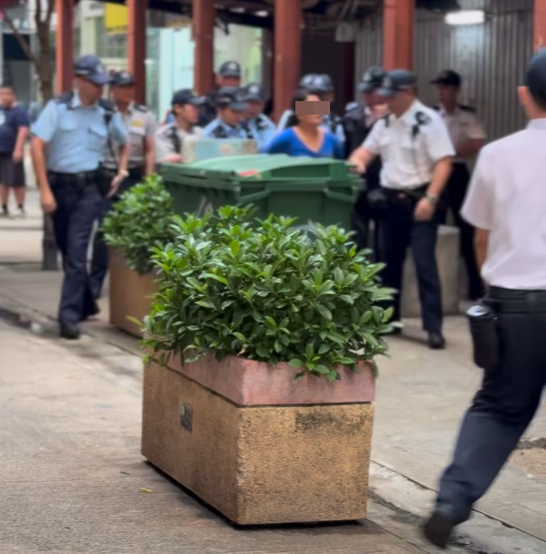 多名食環署職員與警員將女檔主帶走(影片截圖)