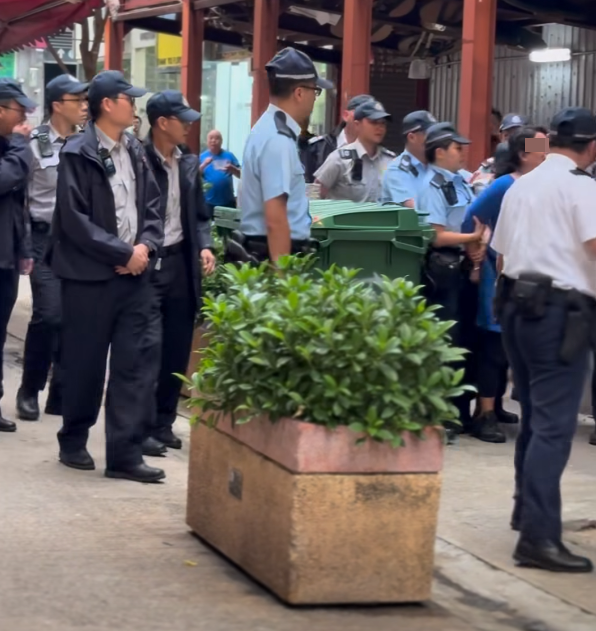 多名食環署職員與警員將女檔主帶走(影片截圖)