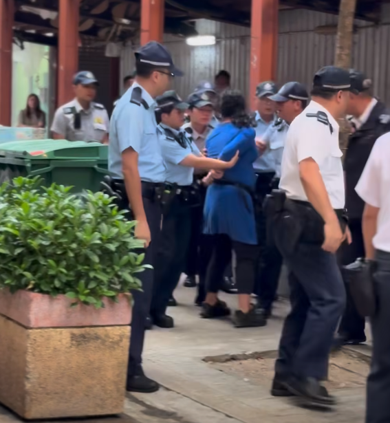 多名食環署職員與警員將女檔主帶走(影片截圖)