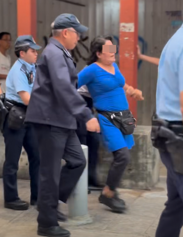多名食環署職員與警員將女檔主帶走(影片截圖)