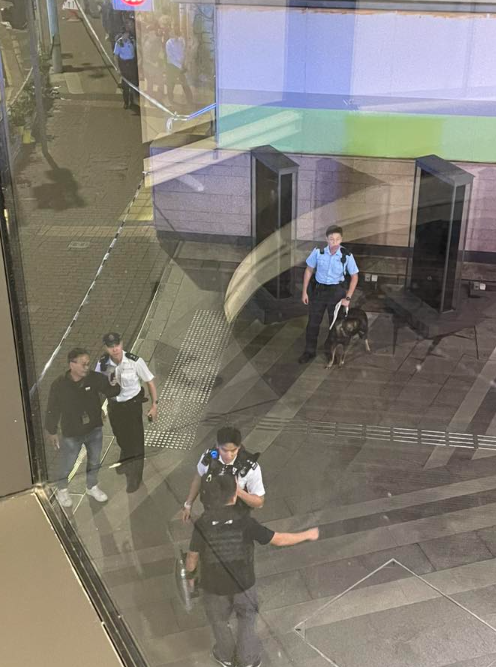 警方接獲一名男子報案指於西區屈地街近香港大學站B1出囗外,被一名男子用刀刺傷腰部,施襲者逃去。現場照片可見地面遺下一灘血漬,警方封鎖現場調查事件,有警員帶同警犬戒備。(西環變幻時FB)