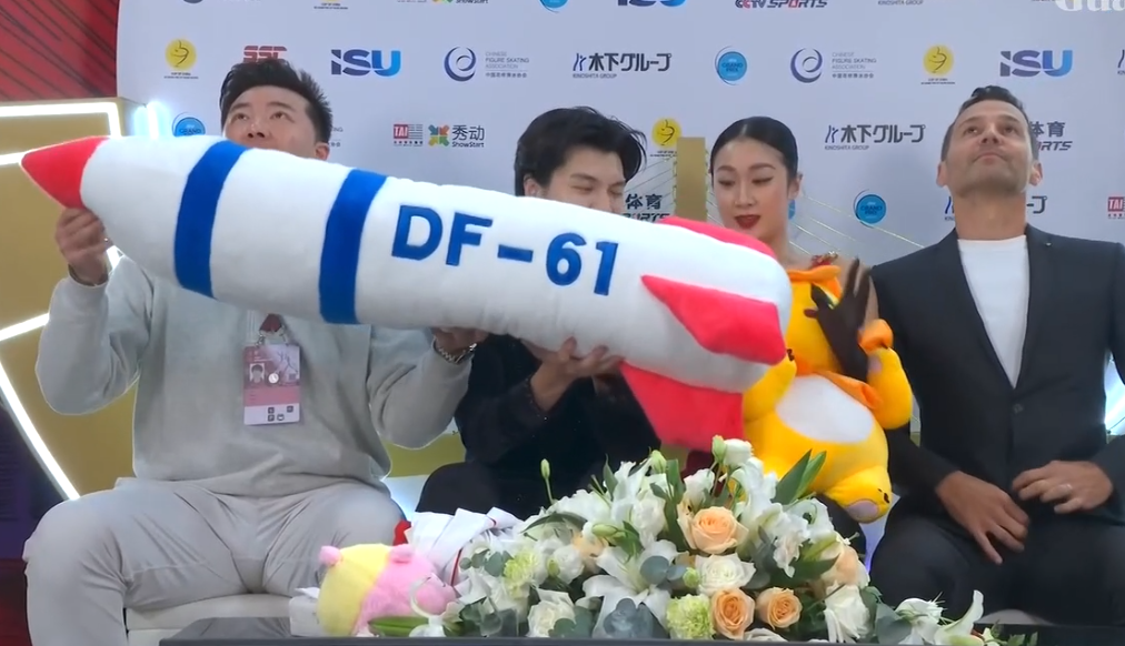 中國盃花樣滑冰大獎賽冰舞賽上周六(25日)於重慶舉行,賽後中國組合任俊霏、邢珈寧在等候分區成績期間,一度拿起觀眾拋入場內、標有「DF-61」字樣的東風61型導彈造型毛絨公仔,並做出模擬飛行動作(影片截圖)