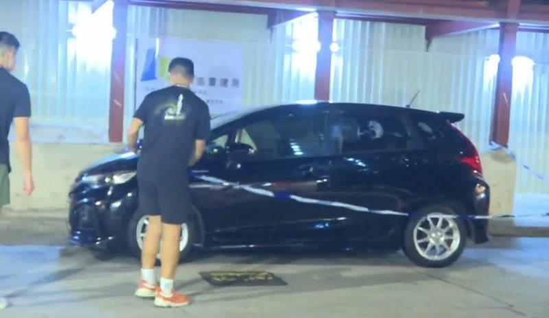 警方於酒店對開圍封一輛疑涉案黑色私家車,並派出緝毒犬協助。(有線新聞截圖)