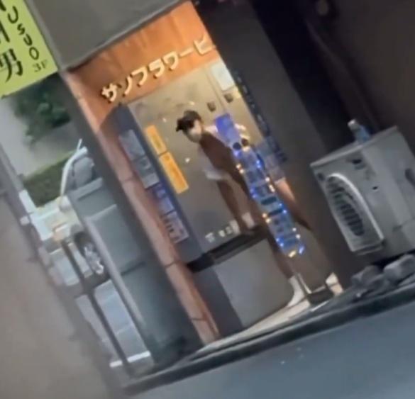 草間在新宿區一棟大樓的出入口附近,露出下半身,引首左顧右盼。(X)